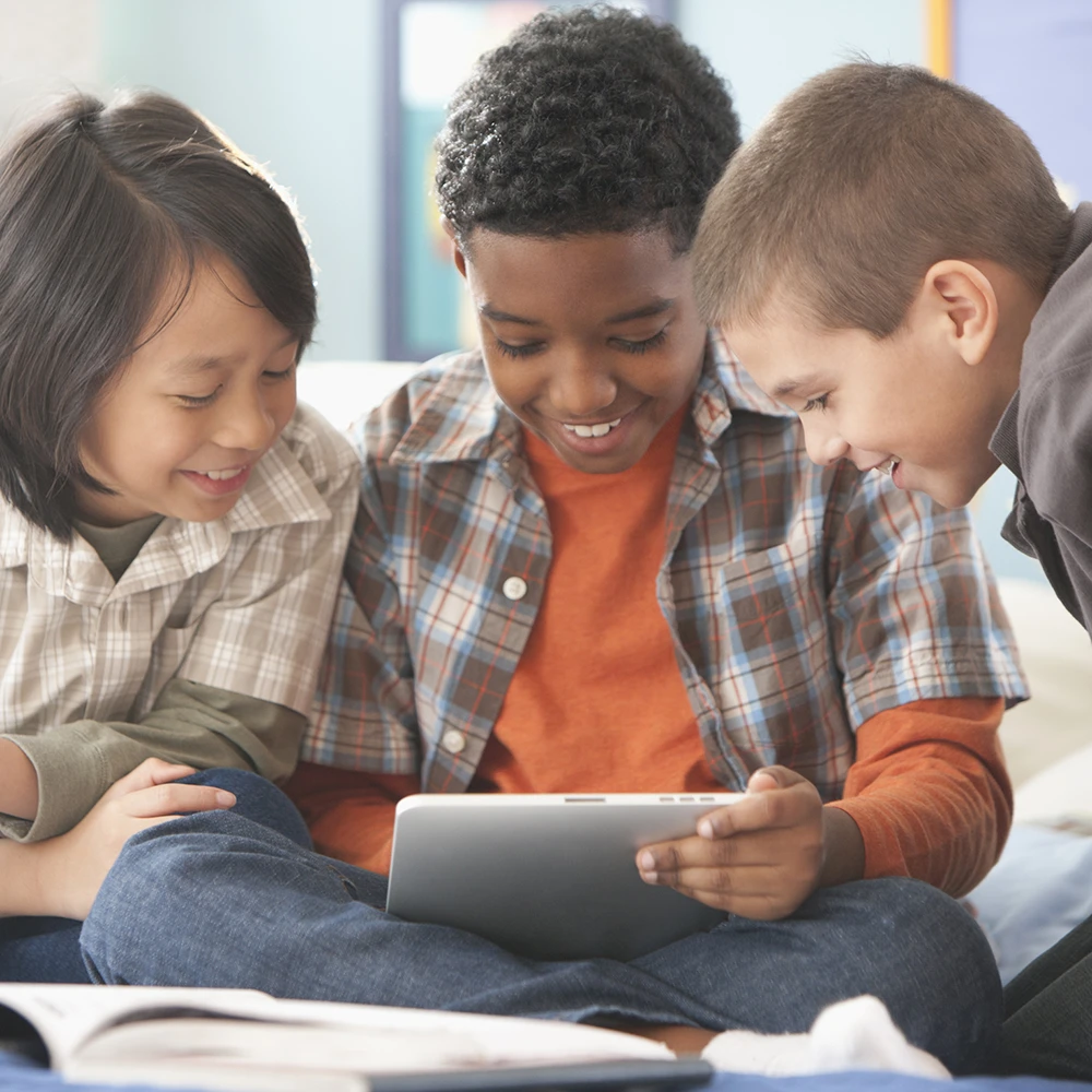 Three children using a computer tablet